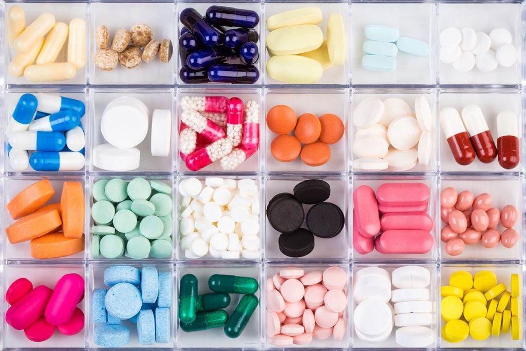 Pote retangular com vinte e quatro divisões contendo diferentes cápsulas de remédio em cada uma dessas divisões | Medicamentos para pressão alta