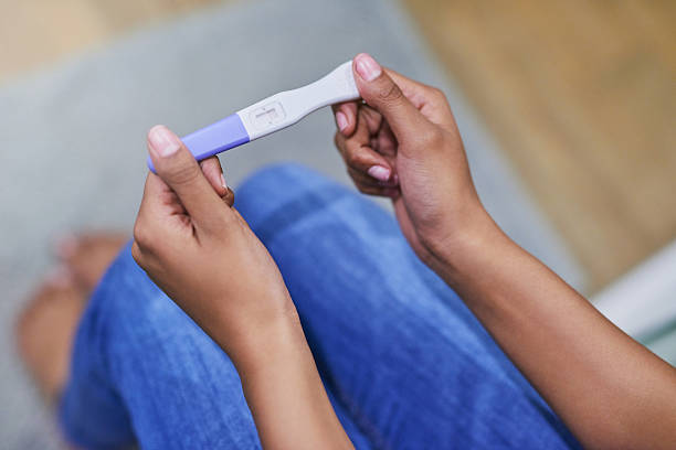 Mulher sentada segura nas mãos um teste de gravidez | Endometriose e gravidez