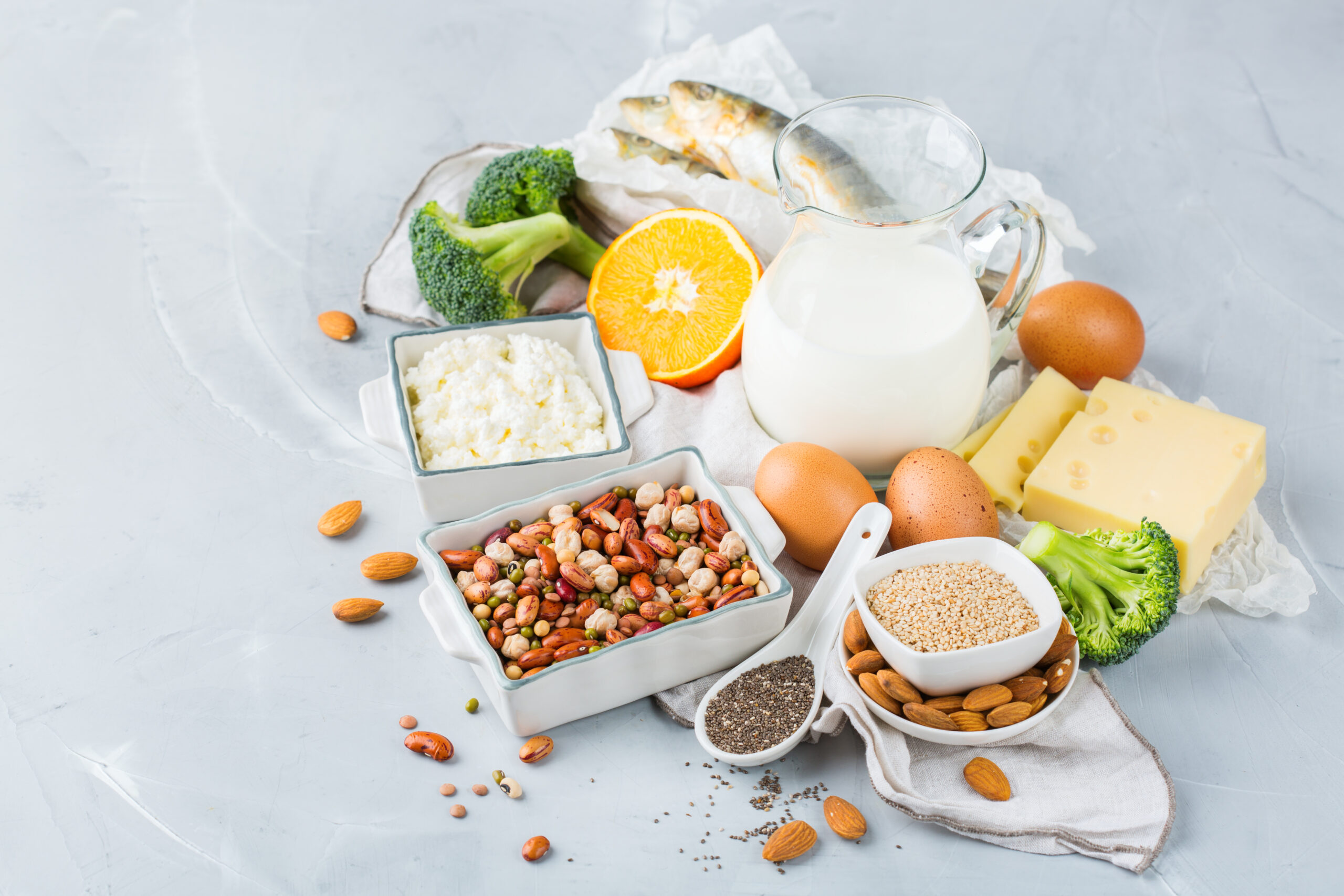 Balanced diet nutrition, healthy eating concept. Assortment of food sources rich in calcium, beans, dairy products, sardines, broccoli, chia seeds, almonds on a kitchen table