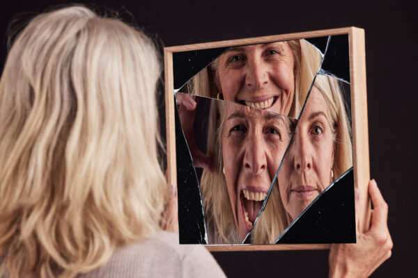 Bipolar woman, broken mirror or reflection of anxiety, depression or psychology, identity crisis or schizophrenia. Depressed face, sad or mature female with mental health, problem or black background.